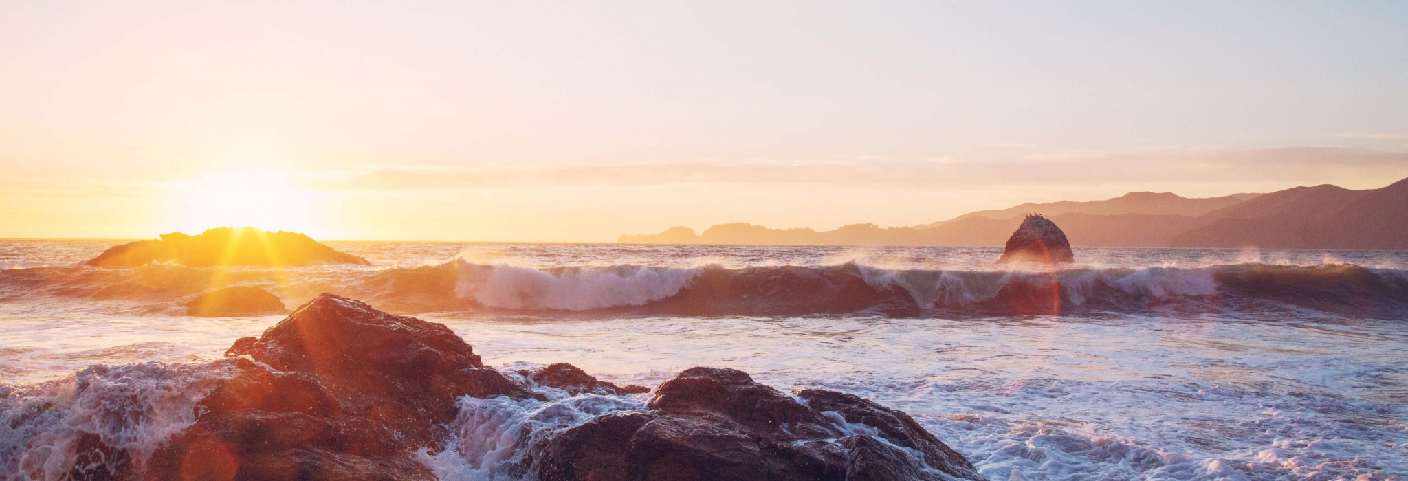 Waves crashing against the rocks at sunset in Cornwall