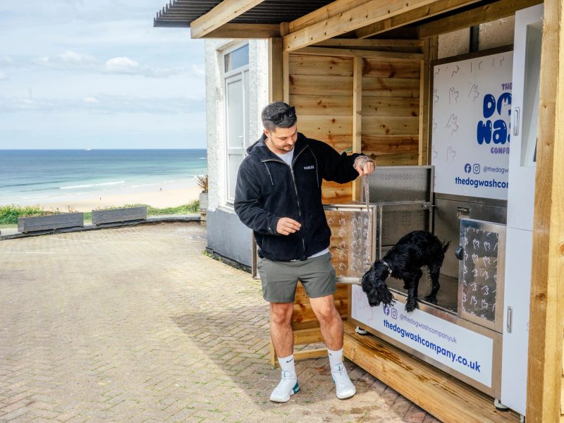 Guest using the dog wash with Fistral Beach behind at The Esplanade Hotel