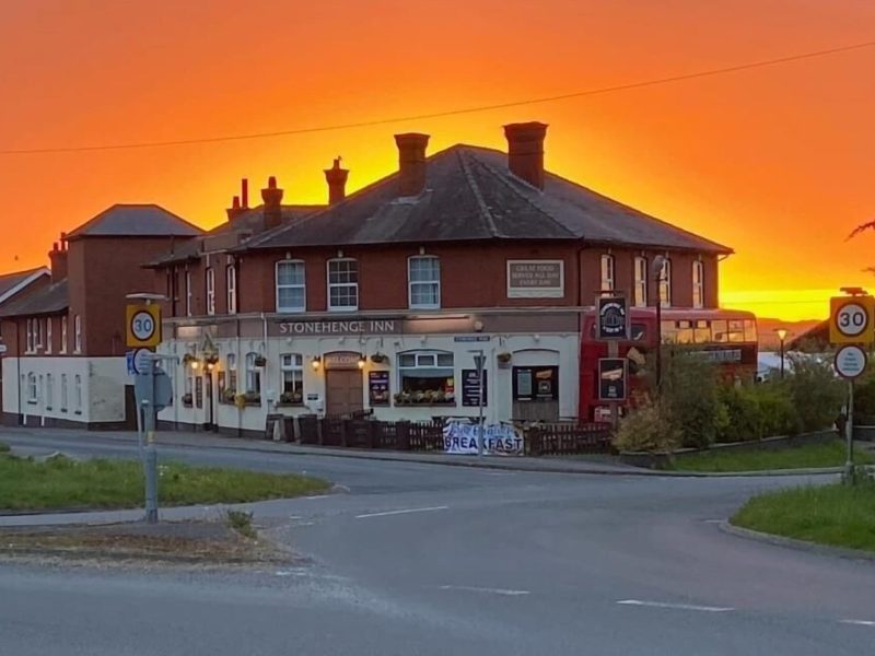 The red-brick Stonehenge Inn in Durrington under an orange sunset sky, the closest pub to Stonehenge