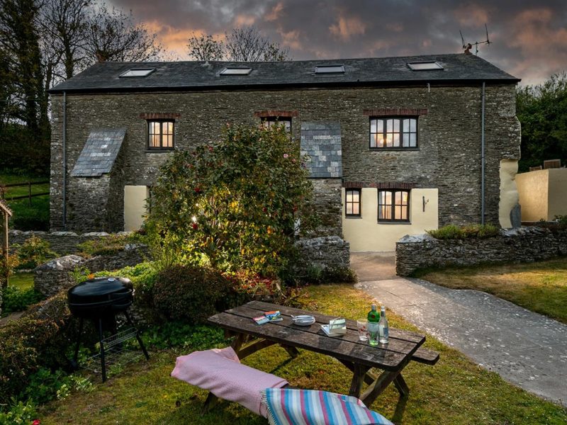Martingale, a dog-friendly stone barn conversion at Pitt Farm, at dusk with its garden, BBQ and picnic table in front