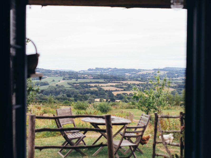 View from the cabin doorway at Mello View across the terrace chairs to the rolling hills of the Axe Valley