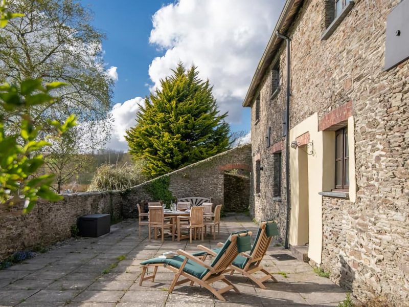 Mullen's sunny walled terrace at Pitt Farm, with sun loungers and outdoor dining beside the stone barn conversion