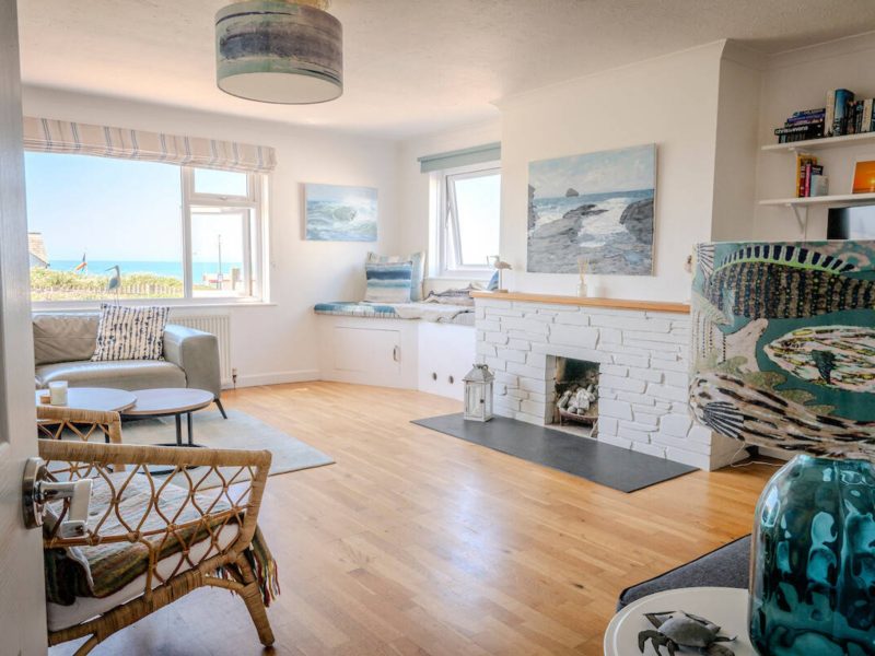Living room with a fireplace and sea views at Trecane Beach House